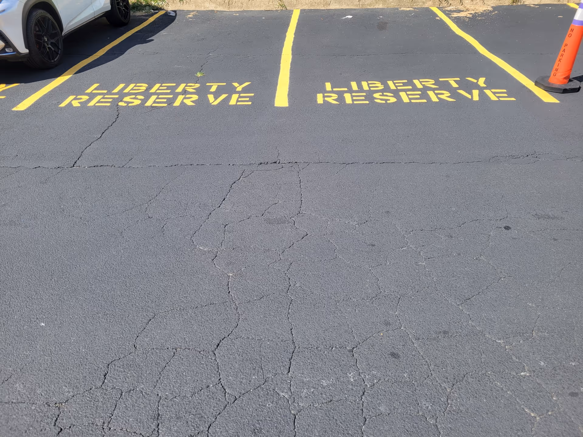 Cracked asphalt parking lot with yellow lines marking Liberty Reserve spaces.