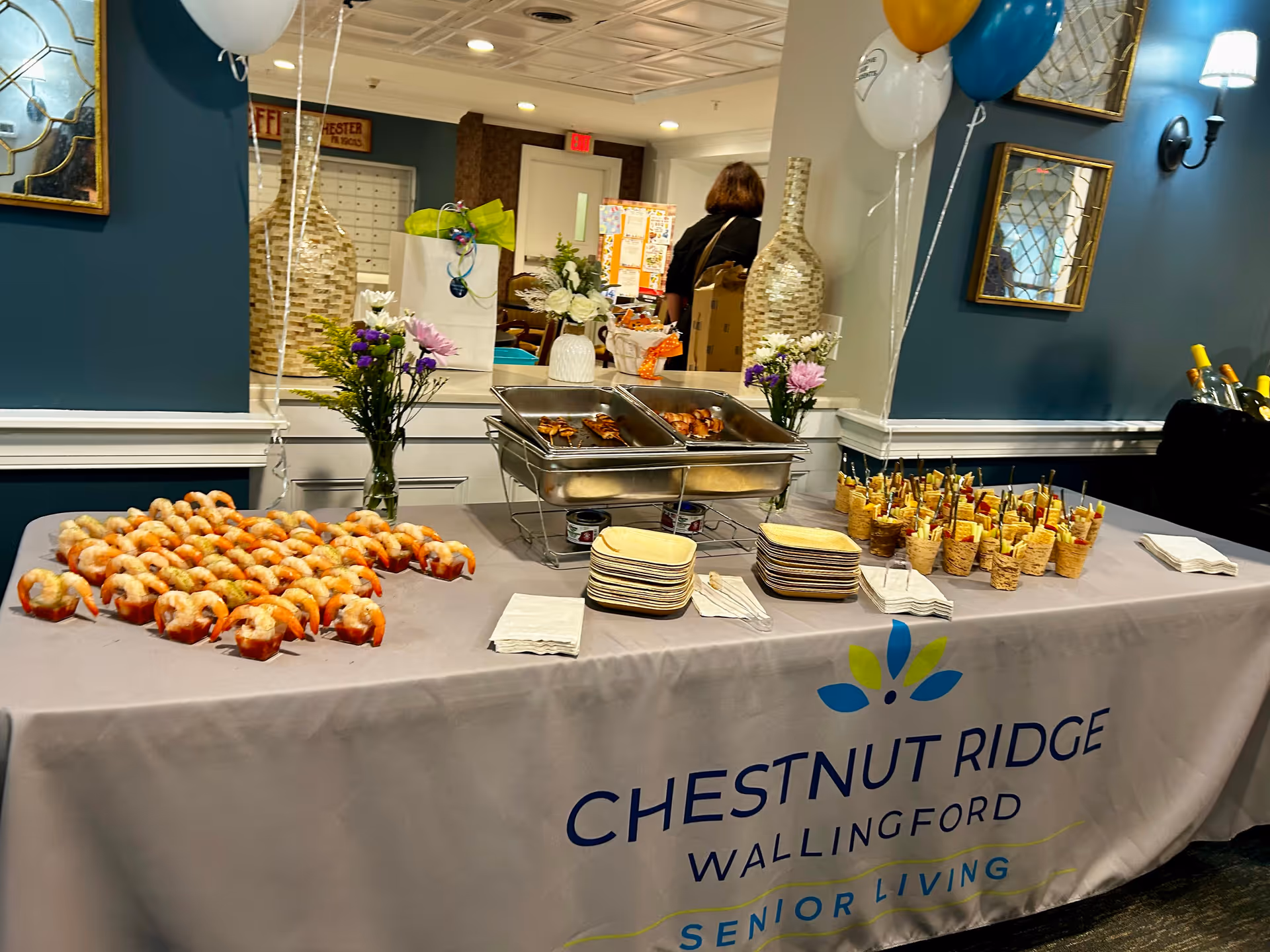 Buffet table with pastries and treats in a decorated indoor senior living facility.