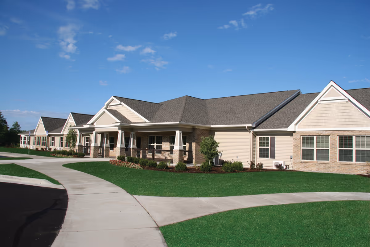 Exterior of Green Acres Lowell senior living center with curved walkway and manicured lawn.