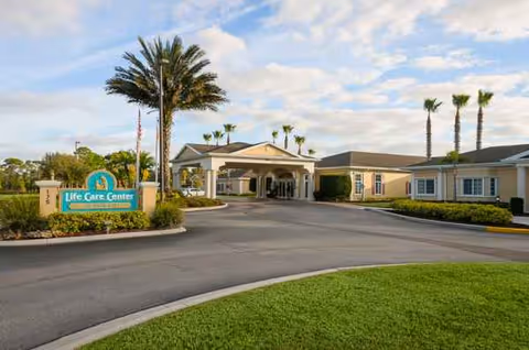 Life Care Center of Palm Bay exterior with driveway, entrance, and palm trees.