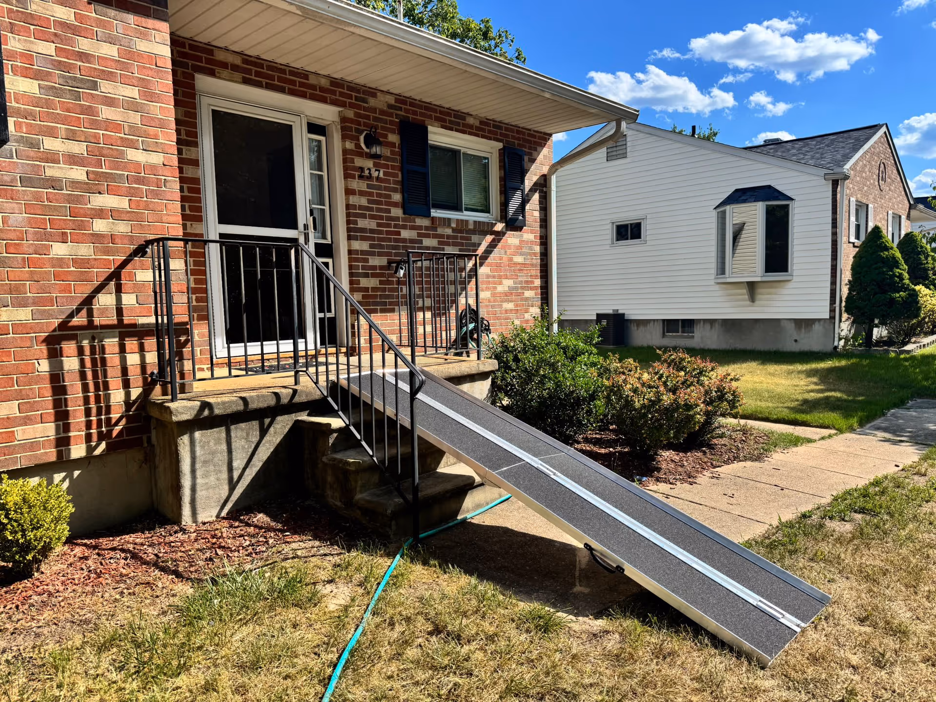 Front entrance of a brick building with stairs and an accessibility ramp.