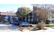Exterior of Tucker House senior living building with parked cars and trees.