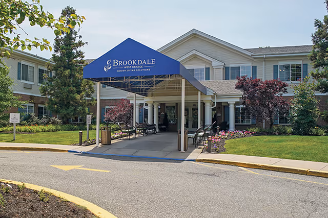 Exterior view of Brookdale West Orange entrance with blue canopy and seating.