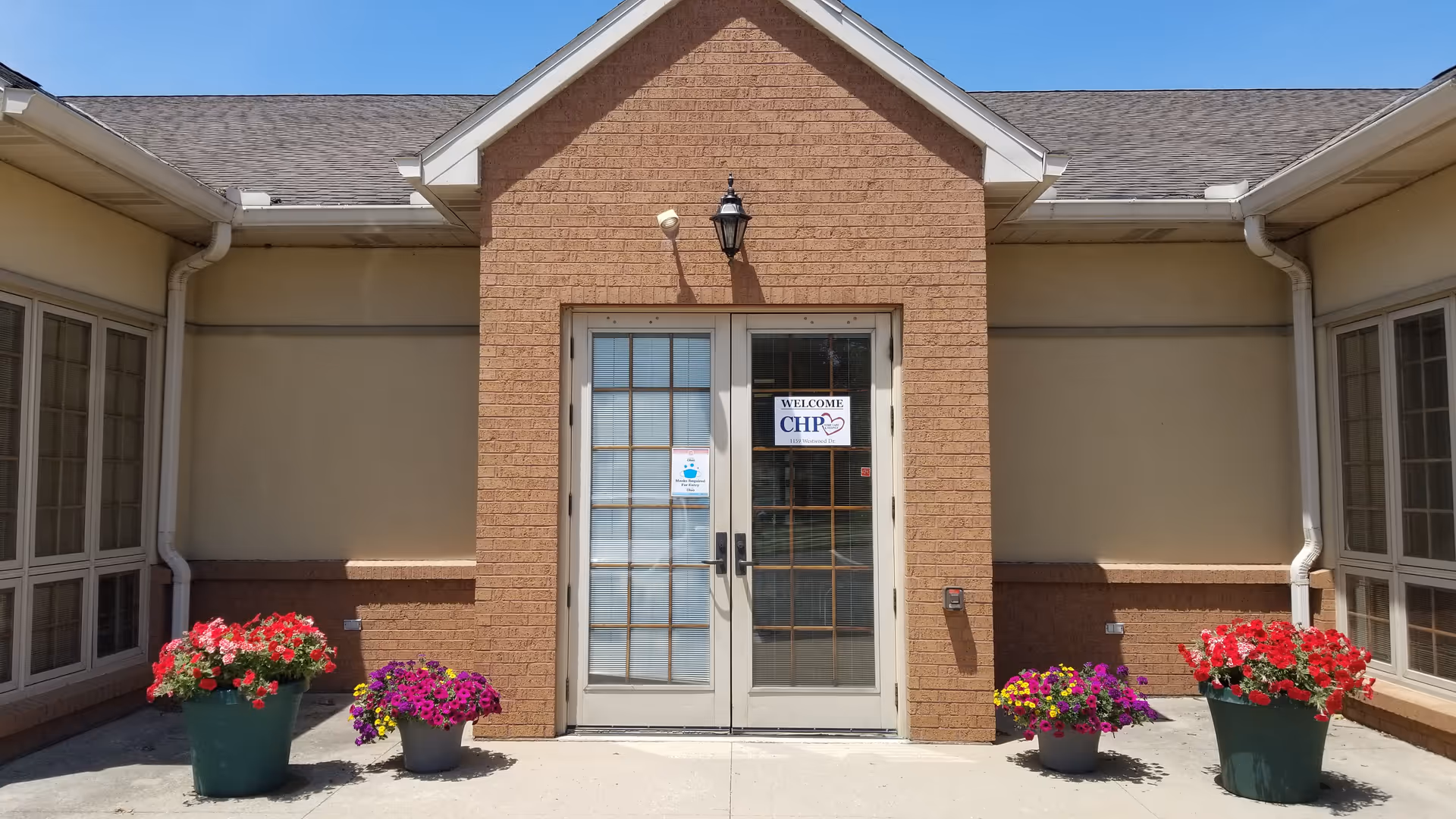 Front entrance of CHP Home Care and Hospice building with brick facade and potted flowers.