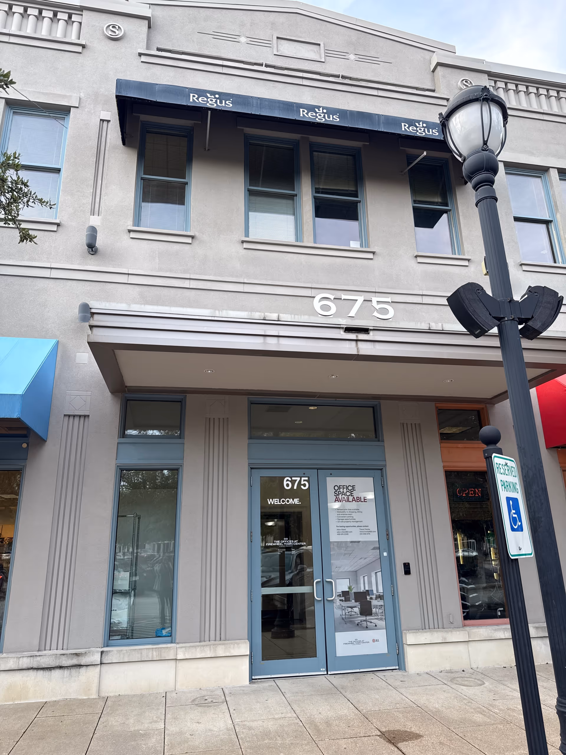 Exterior storefront of a building with blue-framed entrance, address 675, and streetlamp.