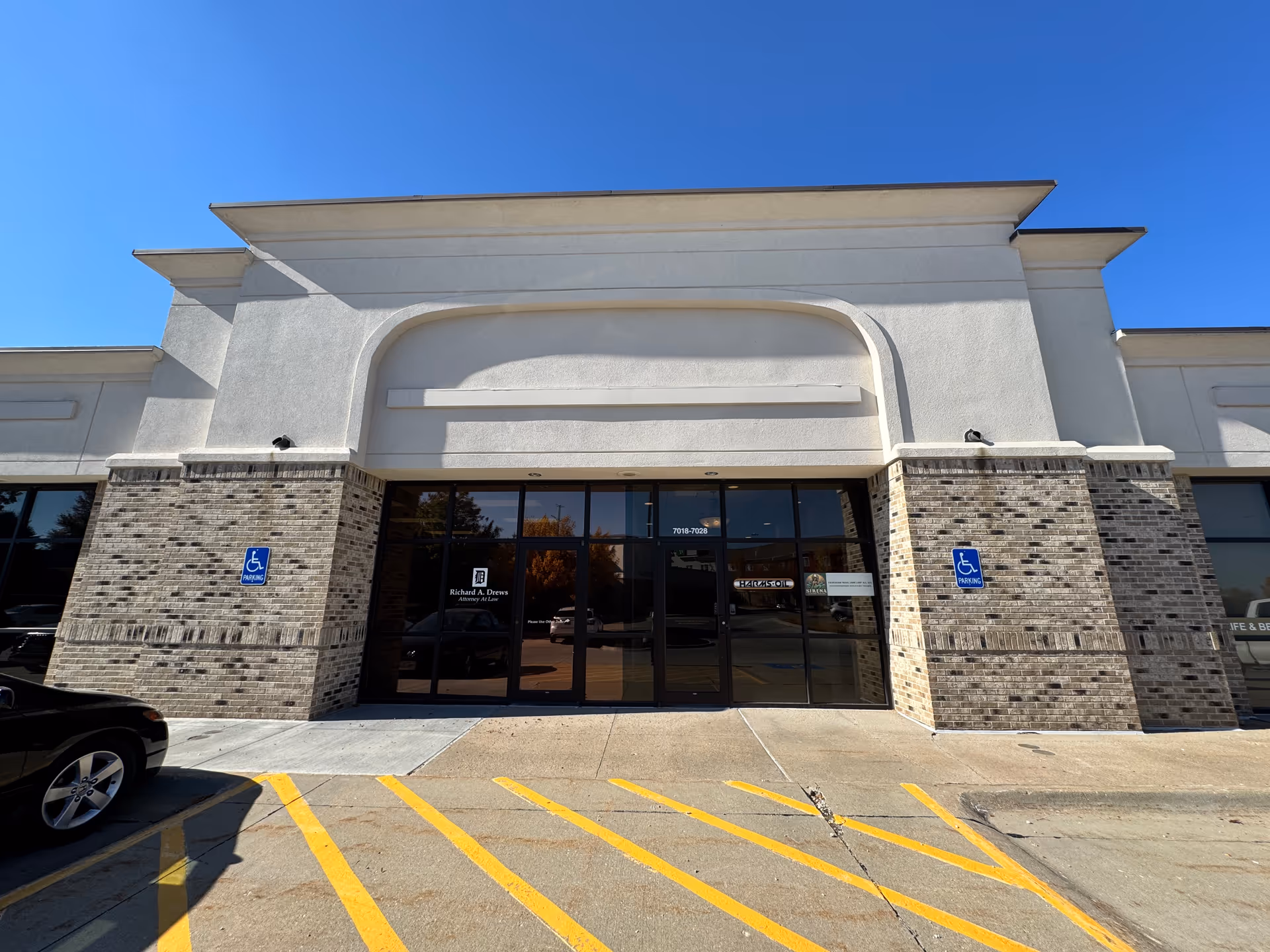 Exterior view of a facility entrance with brick pillars and large glass doors.