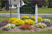 Green Avon Health Center sign with colorful flowers in front.