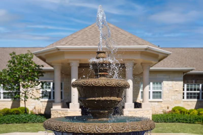 Stone tiered fountain in front of a senior living facility entrance