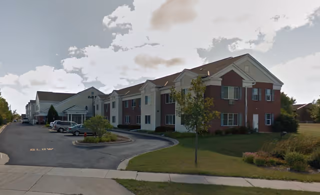 Exterior view of Cornerstone of Oak Creek senior living buildings with cars and landscaping.