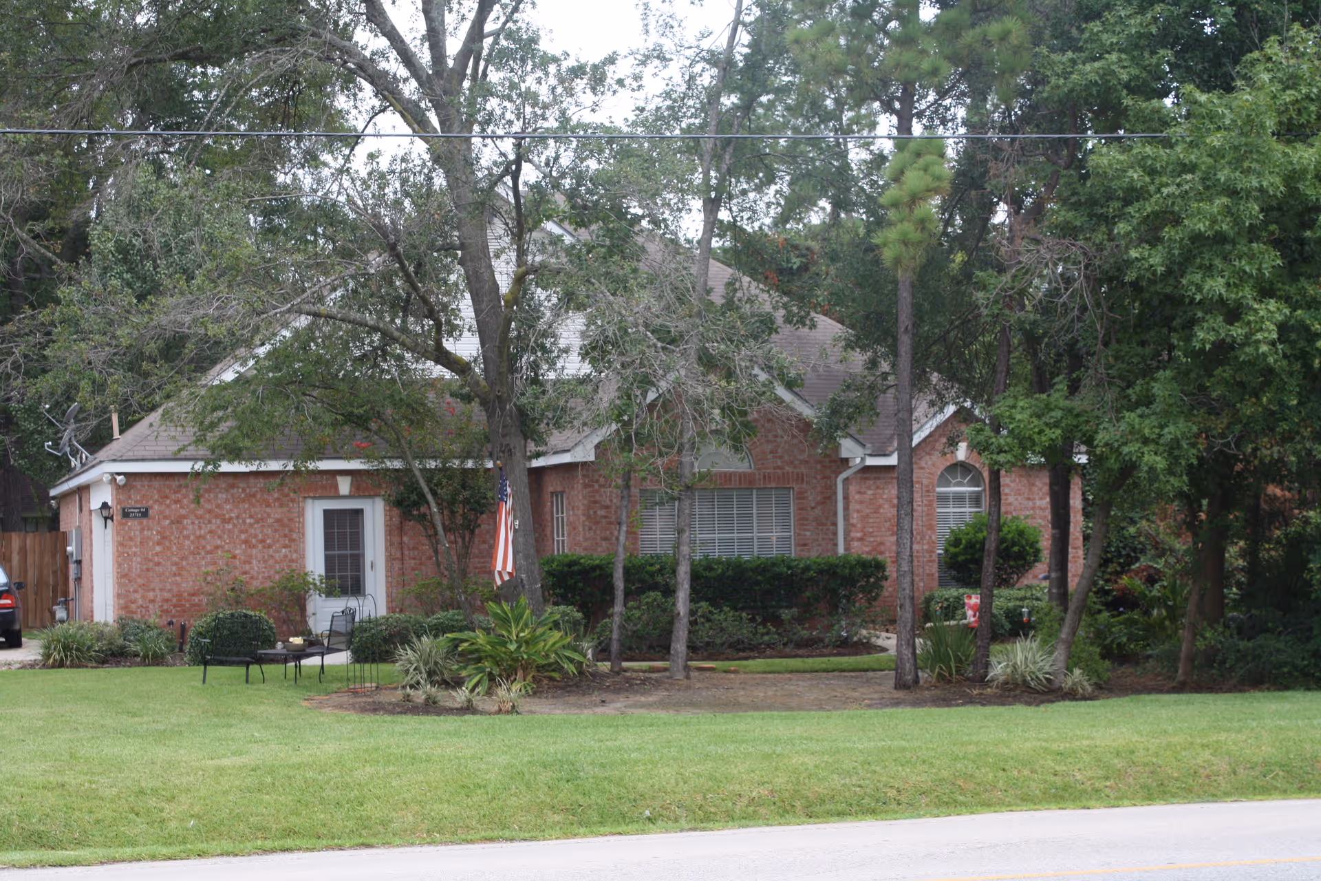 Brick, single-story Willis House facility with a front lawn, trees, and outdoor seating.