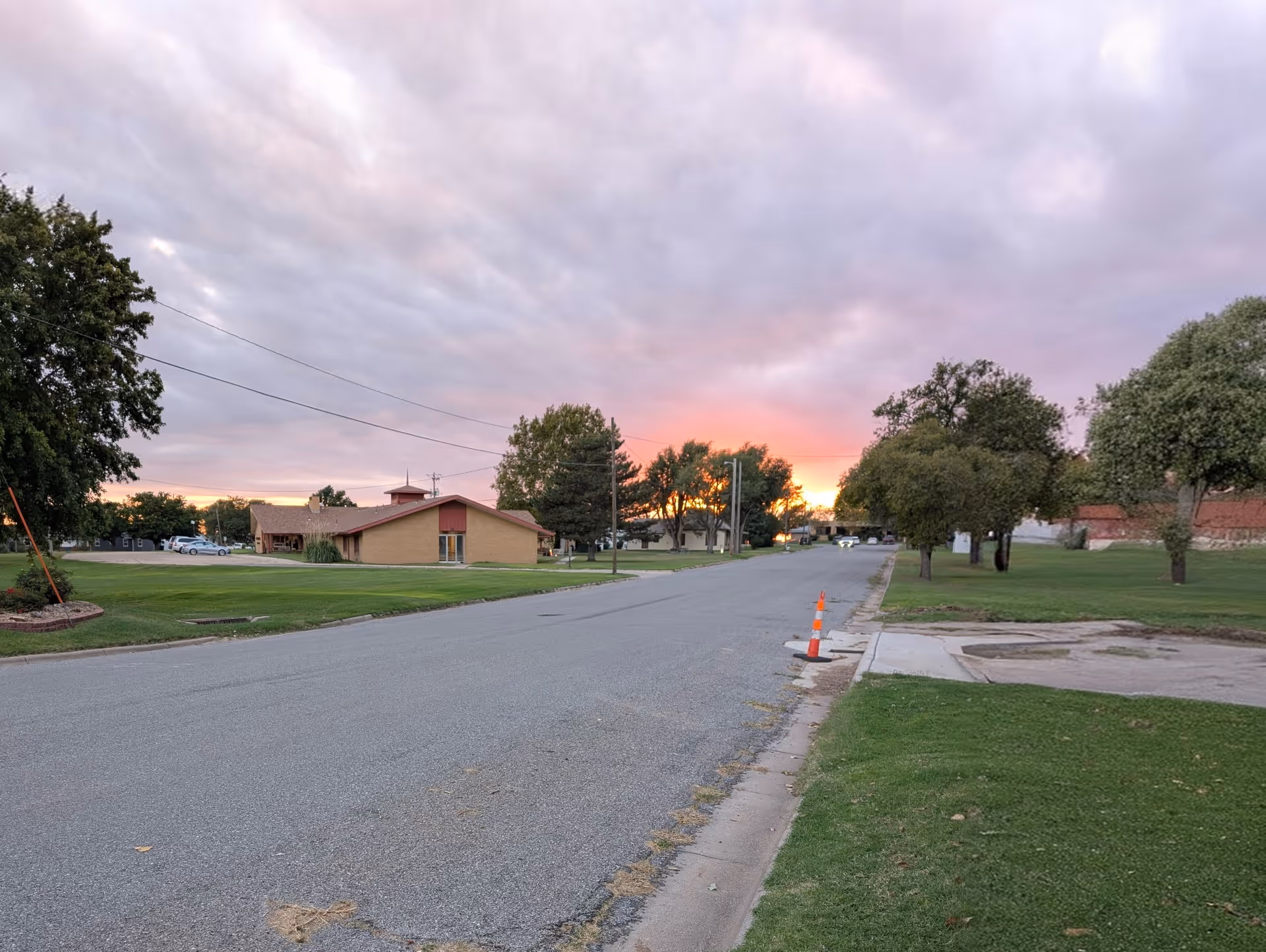 Sunset over a quiet street beside the beige Pioneer Lodge building.