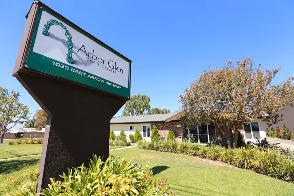 Front view of Arbor Glen Care Center sign with building and well-kept landscaping.