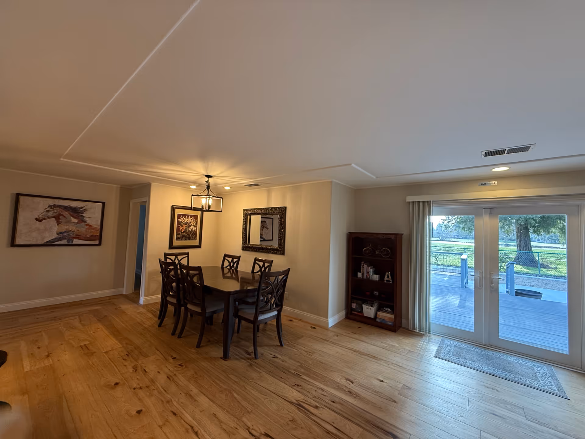 Dining room with wooden table and chairs, artwork, and glass doors to outside