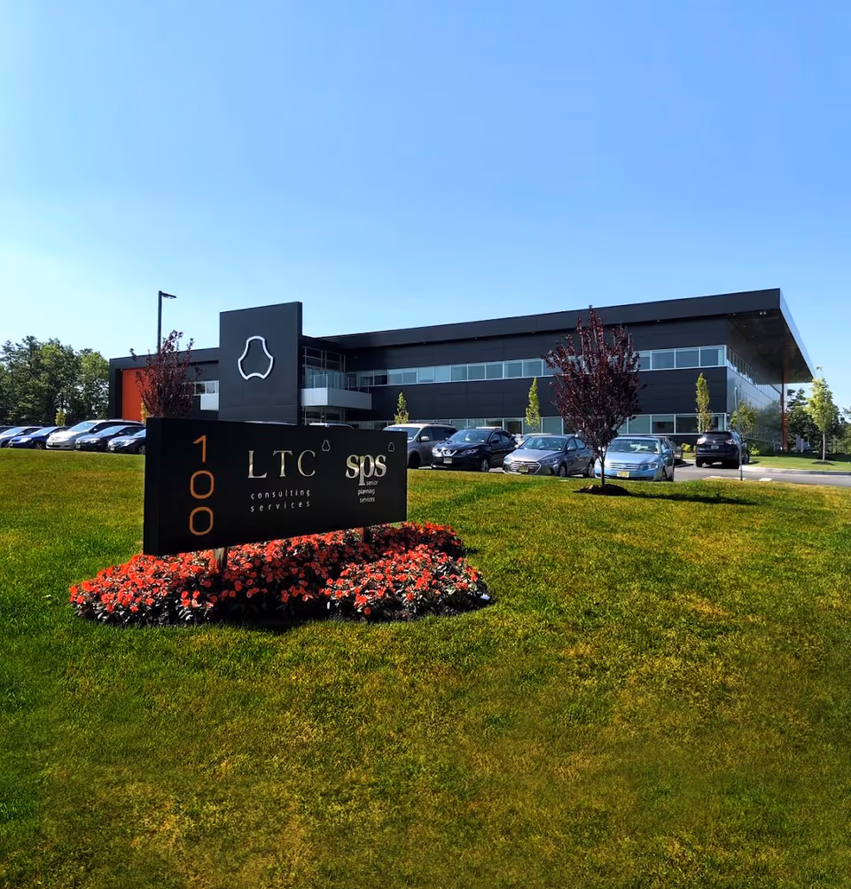 Modern two-story office building with a prominent sign and a parking lot under blue sky