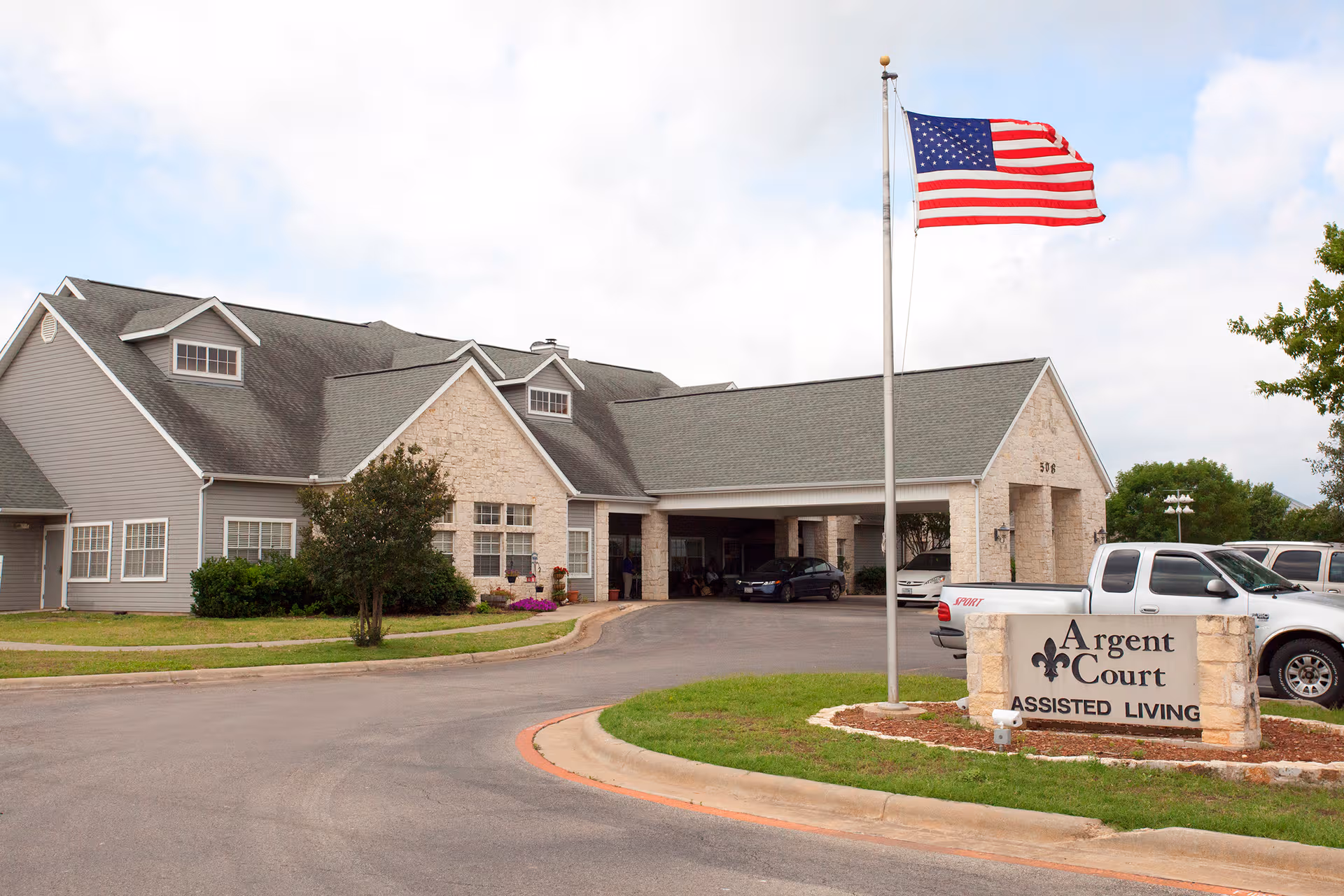 Exterior view of Argent Court Assisted Living facility with flagpole and entrance.