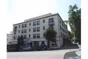 Front exterior of Bret Harte Retirement Inn, a three-story beige building on a busy street.