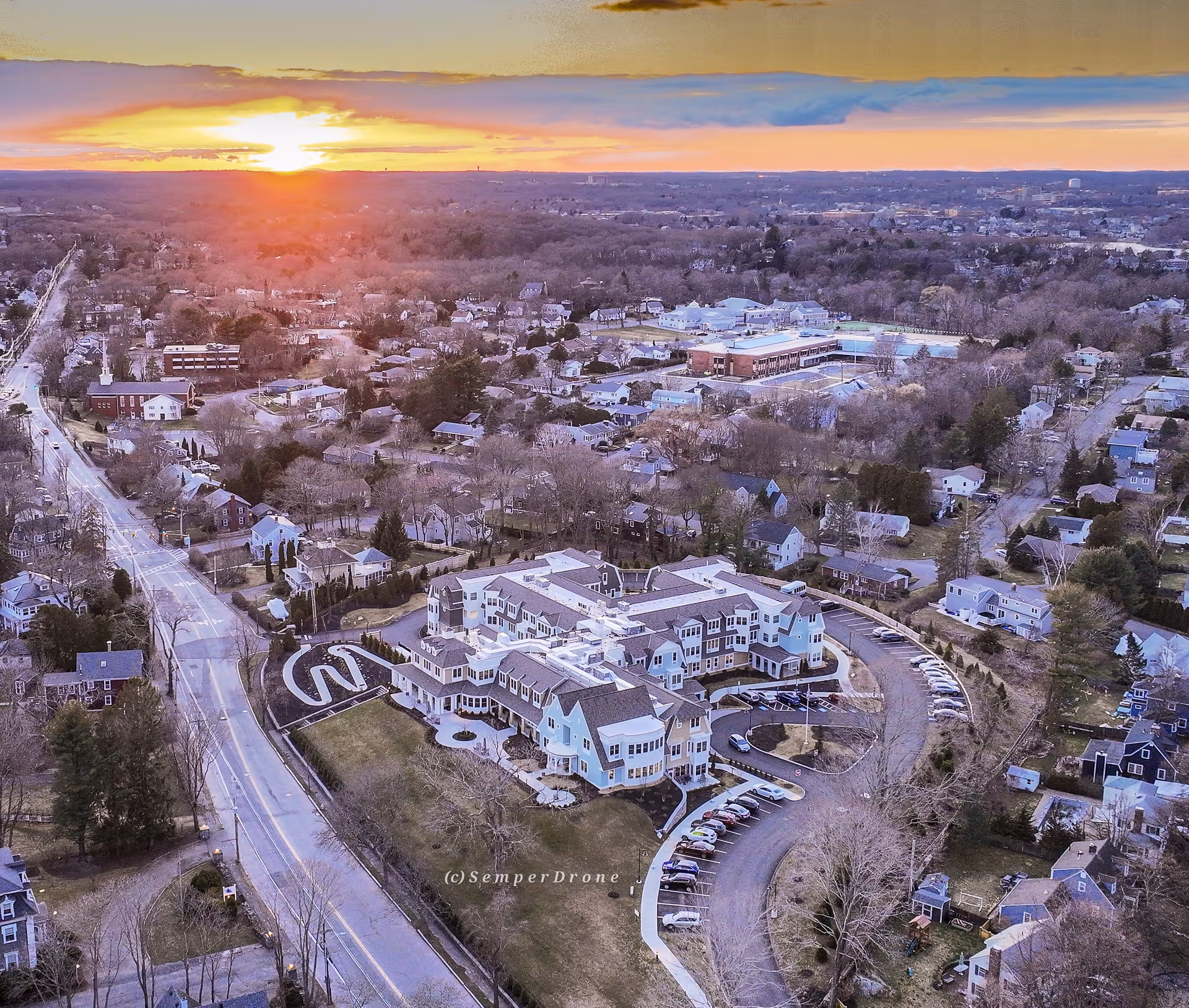 Aerial view of The Mariner Marblehead senior living campus at sunset with a circular driveway.