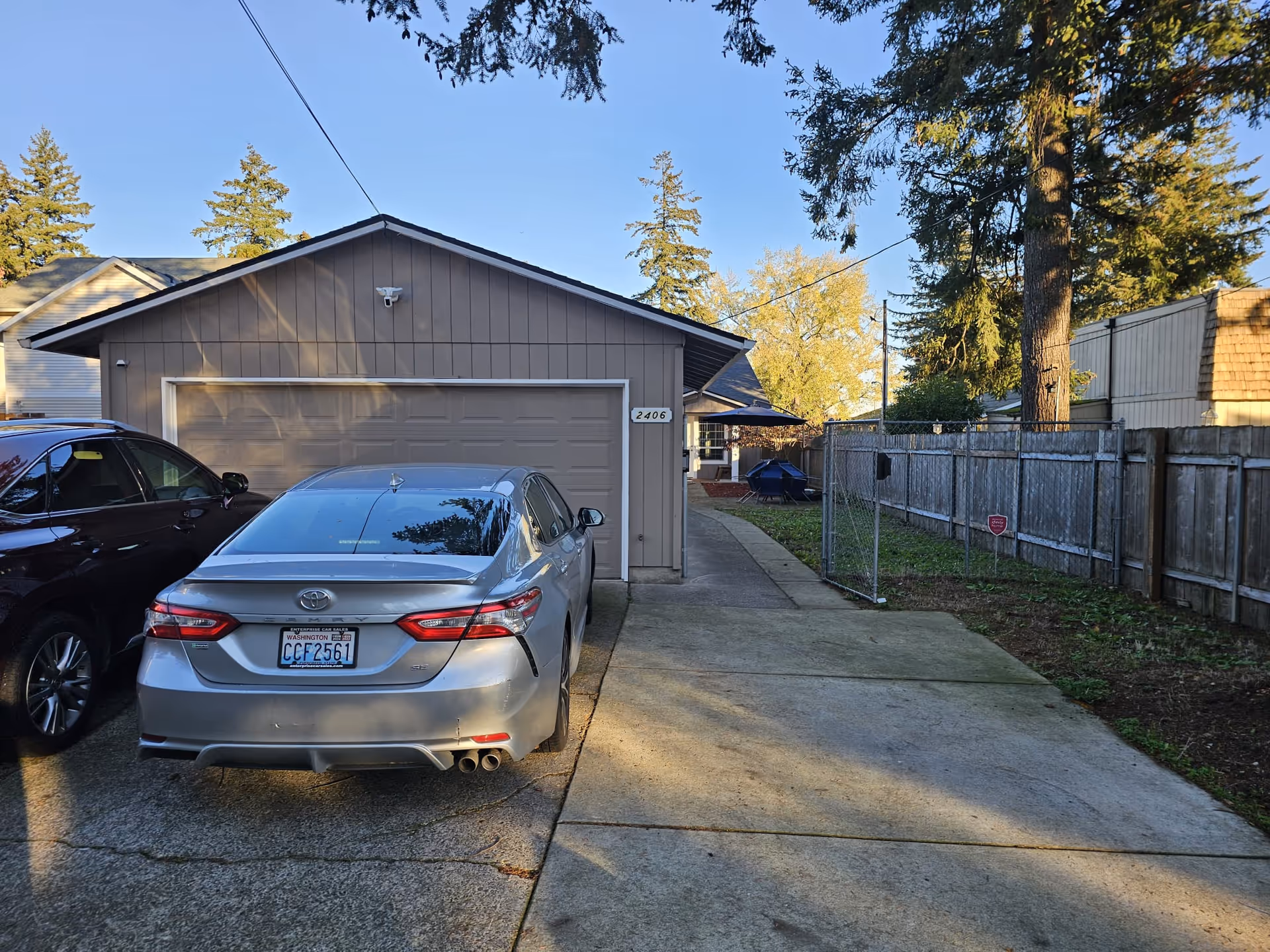 Exterior of a single-story home with a garage, driveway, and parked cars.