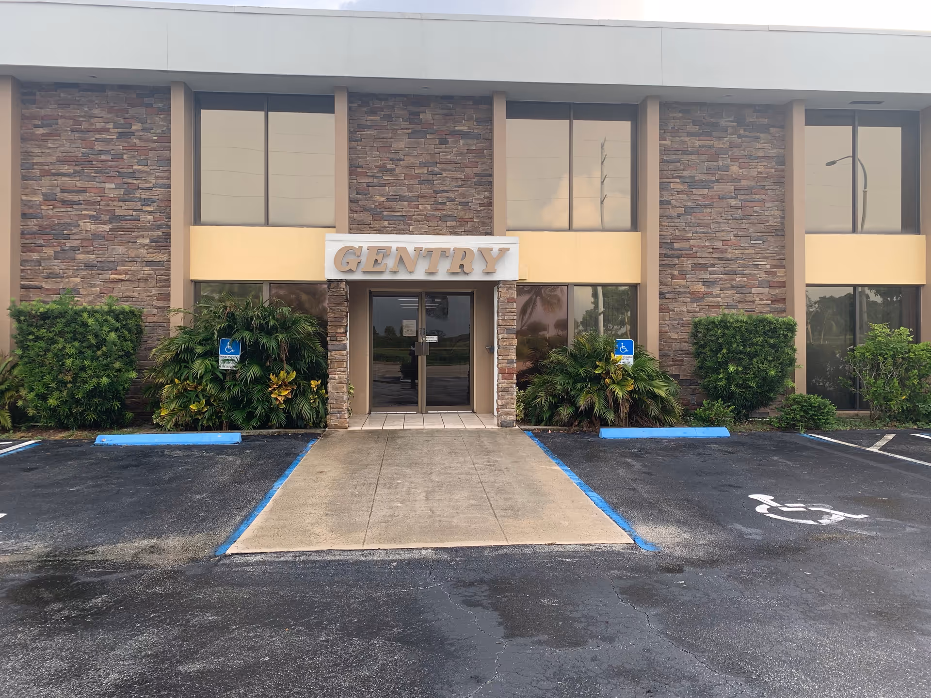 Front of a building with stone facade, glass doors, and a GENTRY sign.