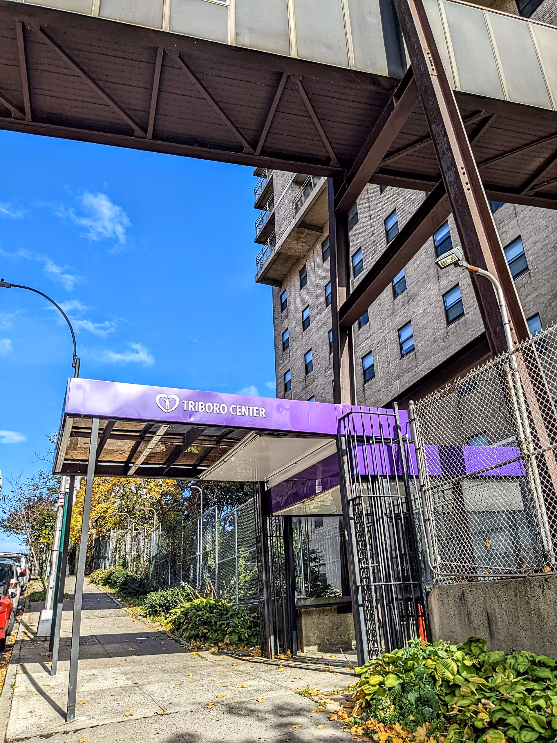 Exterior view of Triboro Center entrance with purple sign and glass canopy.