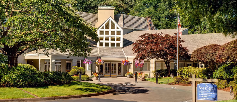 Exterior view of SpringRidge at Charbonneau with entrance, trees, and hanging flower baskets.