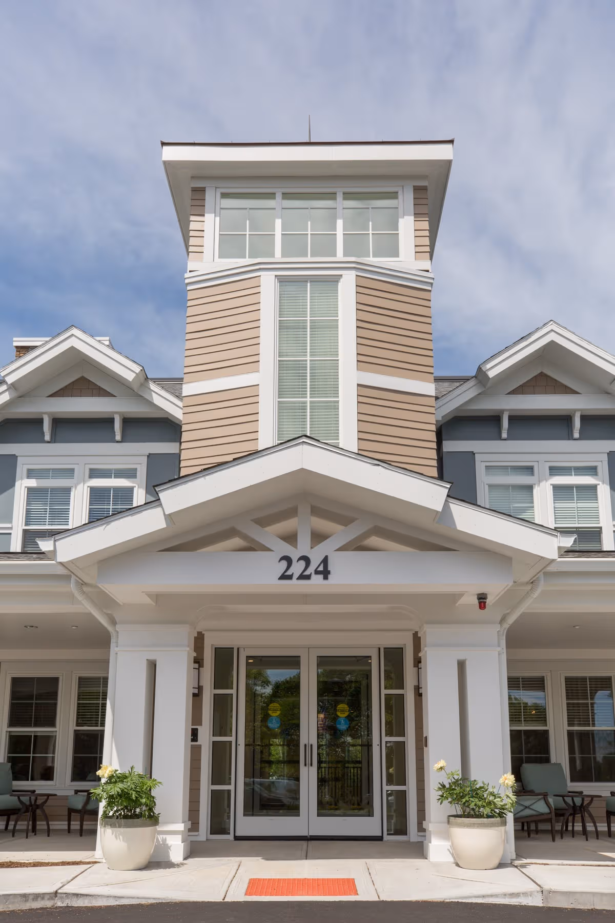 Exterior view of a senior living facility entrance with columns and seating.