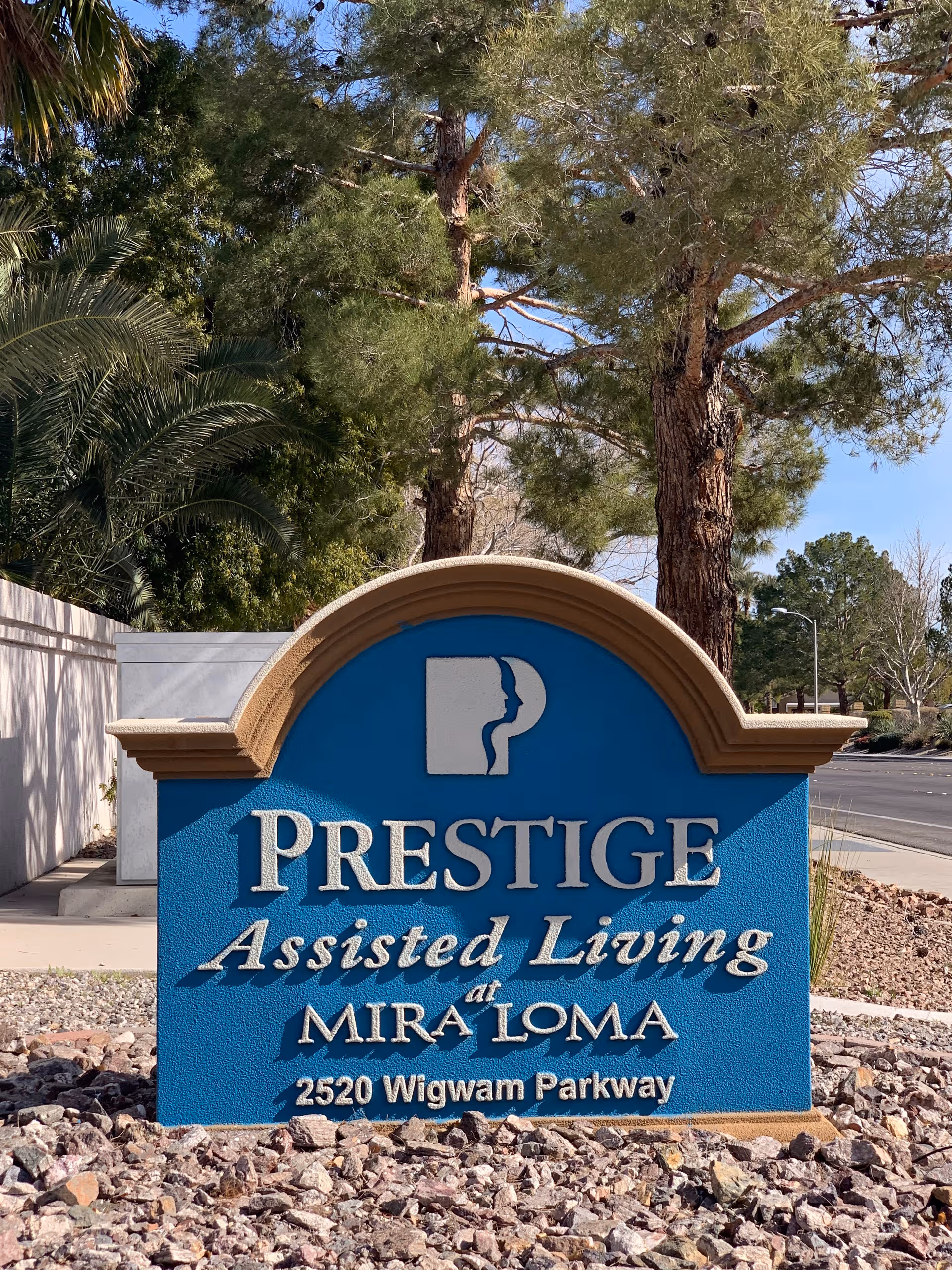 Blue Prestige Assisted Living sign for Mira Loma in rocky landscaping.