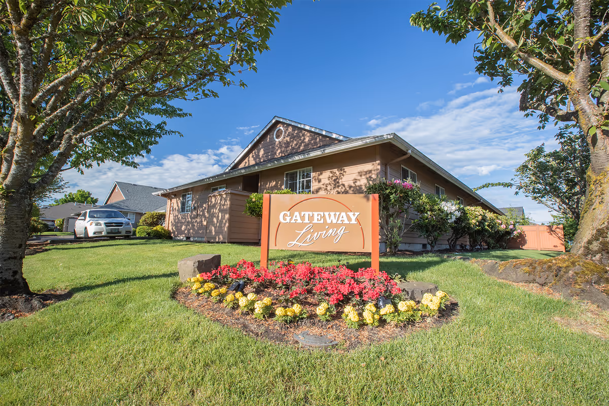 Landscaped front yard with a sign reading "Gateway Living" in front of a single-story building.
