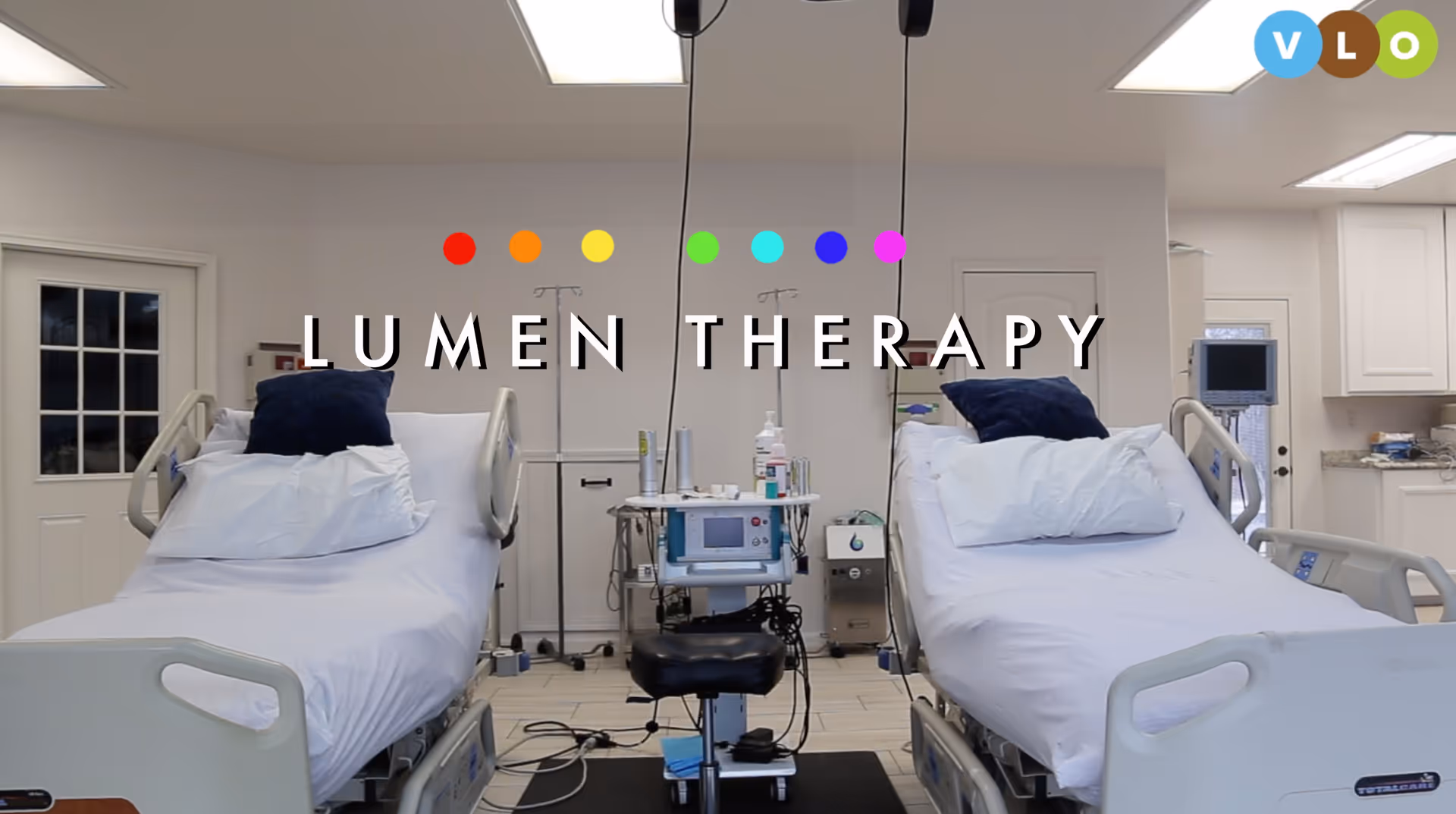 Two hospital beds with white linens and medical equipment in a bright Lumen Therapy room.