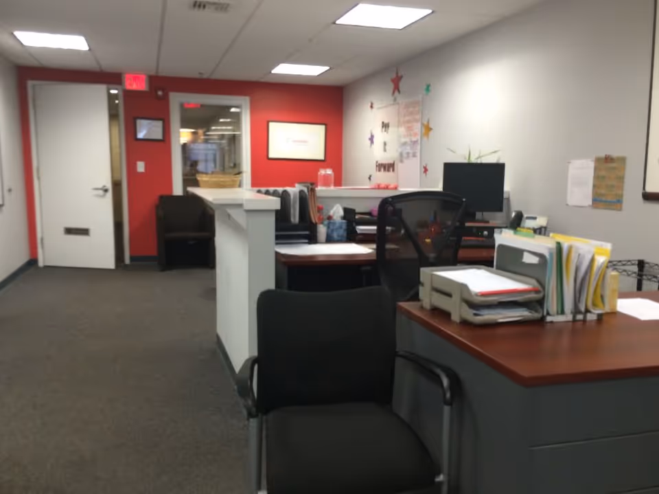 Office reception area with desks, chairs, and paperwork inside a senior care facility.