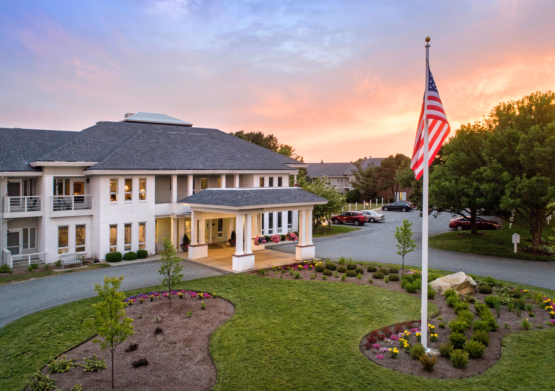 Exterior view of Maplewood at Mayflower Place with entrance, flagpole, and landscaped grounds.