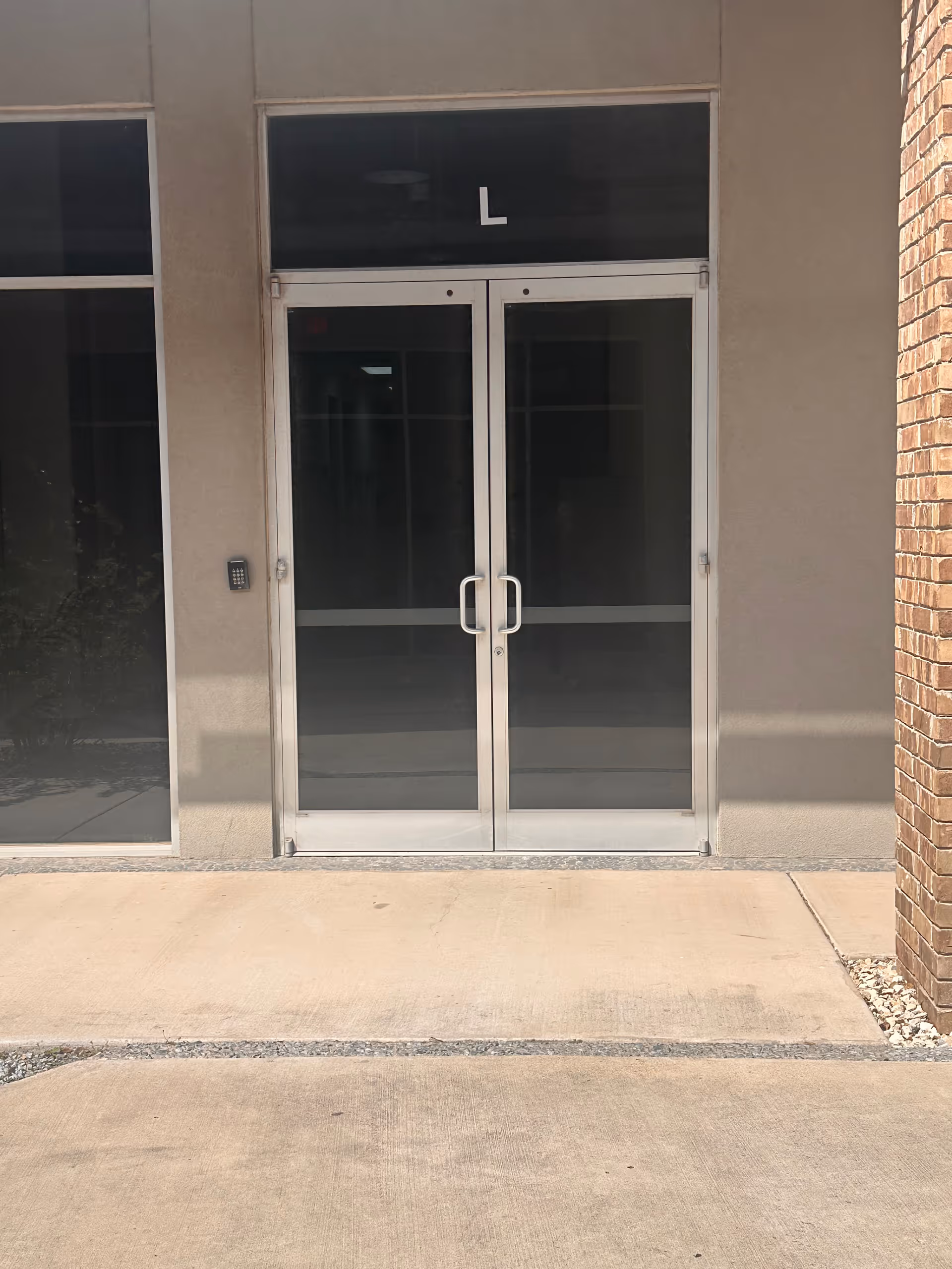 Glass double doors of a facility entrance with a keypad on the left