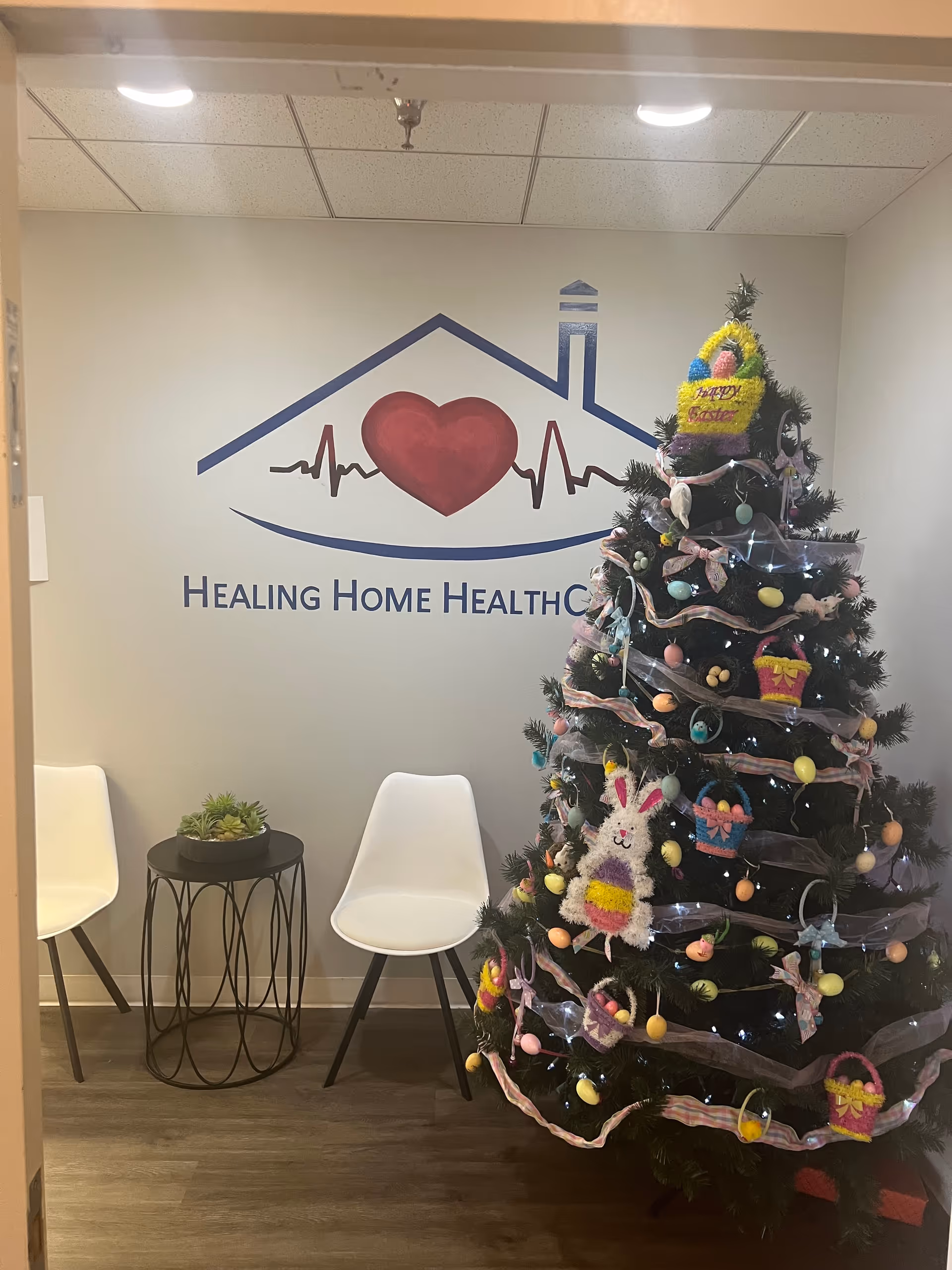 Interior waiting area with a Christmas tree, logo wall, and white chairs.