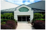 Front entrance of The Summit at Plantsville with glass doors and manicured shrubs.