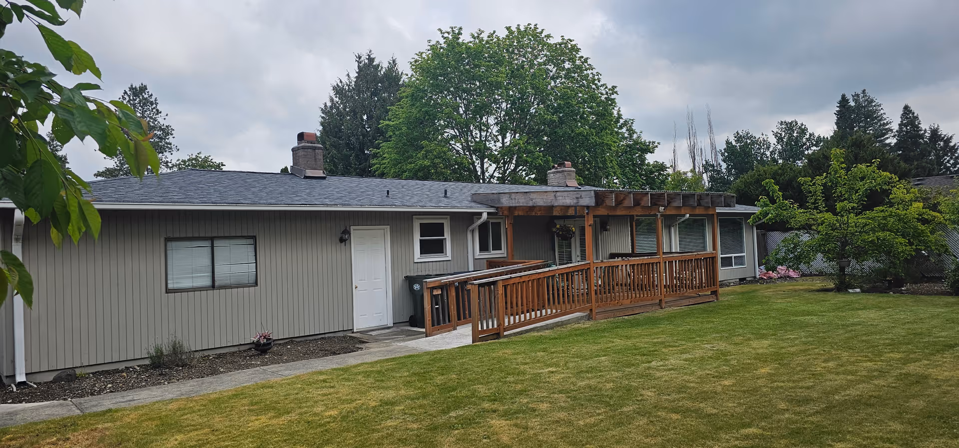Single-story senior living facility exterior with wooden ramp and green lawn.