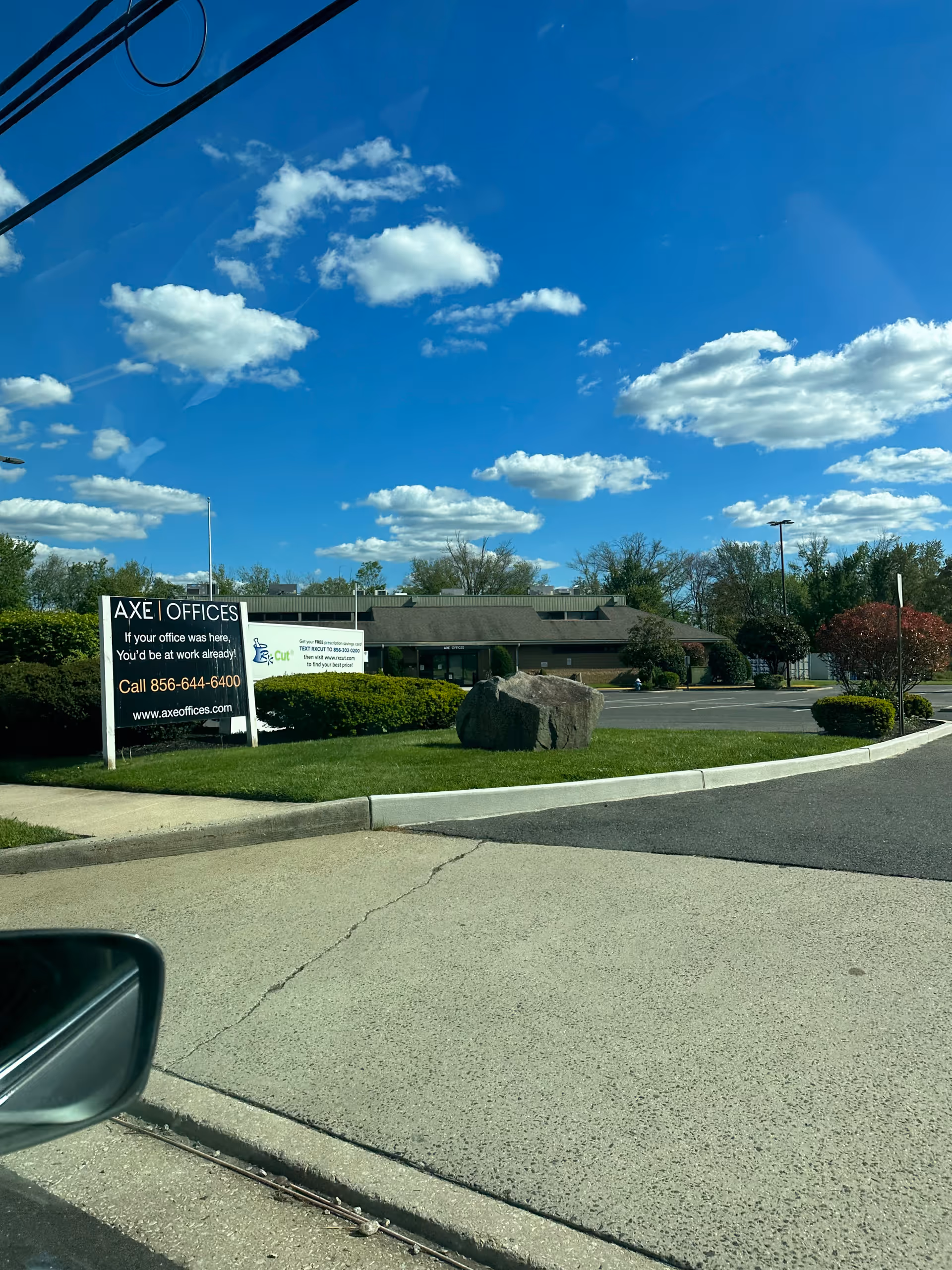 Exterior view of a low-rise office building with an AXE Offices sign and parking lot.