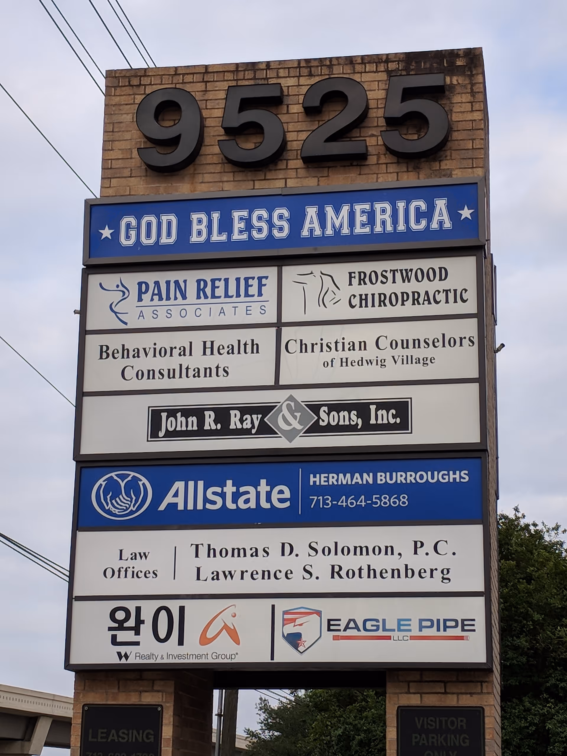 A tall brick sign structure with multiple business panels and 9525 at the top.