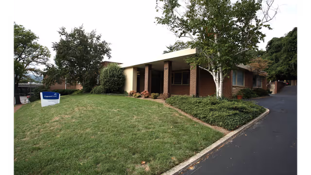 Exterior view of Carilion Clinic Hospice brick facility with curved driveway and landscaped lawn.
