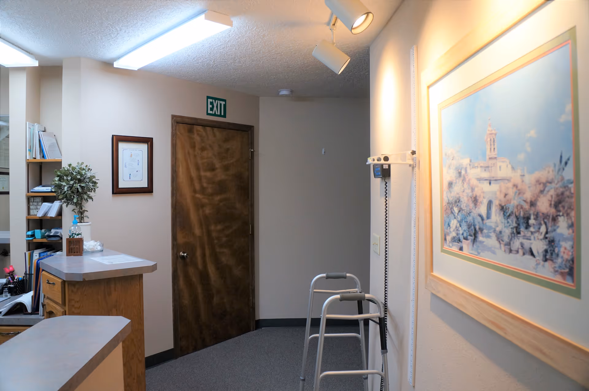 A hallway inside Evergreen Medical Center PS with a walker and framed art.