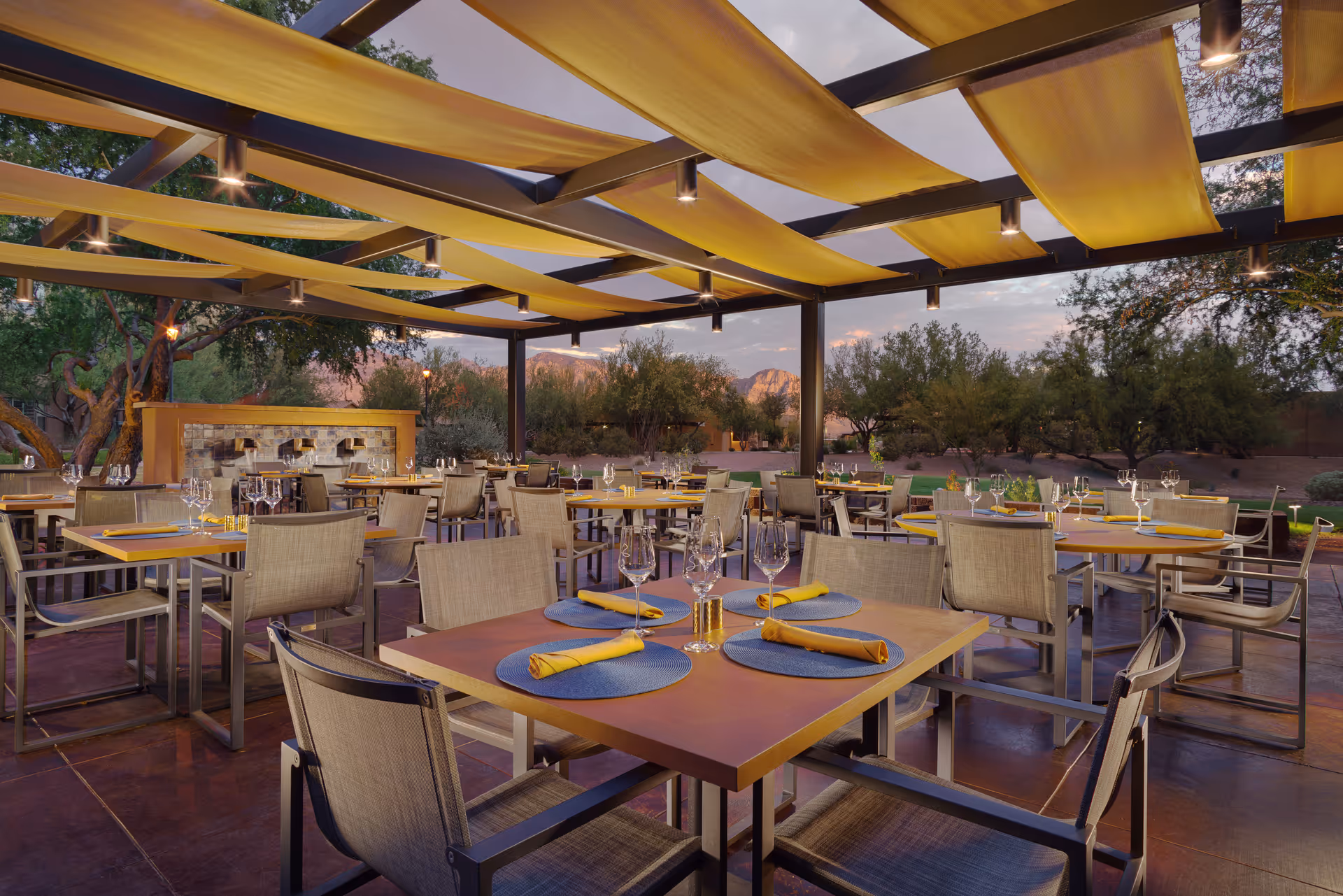 Outdoor dining patio with yellow canopies and neatly set tables for residents.