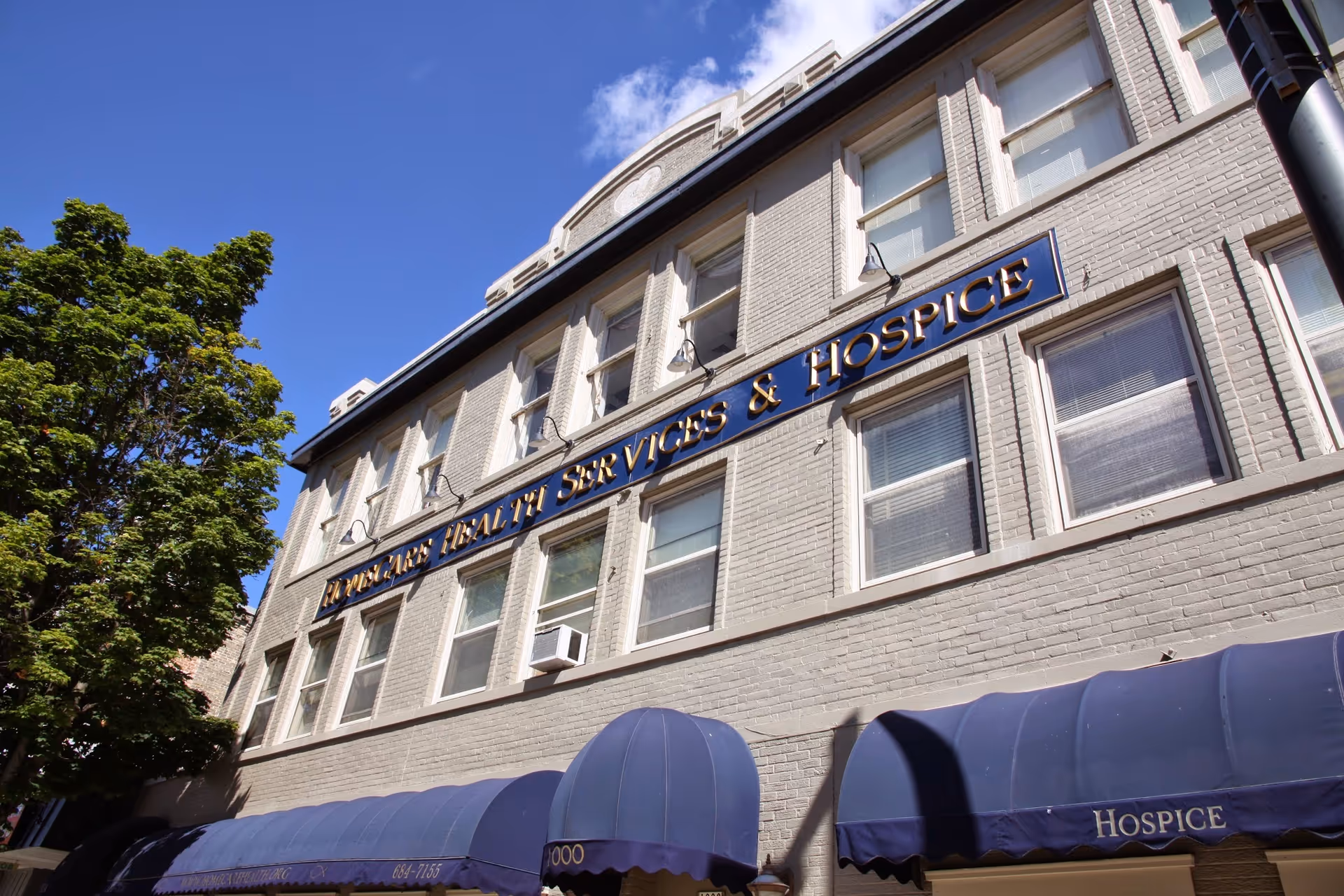 Exterior view of a brick facility with signage and blue awnings.
