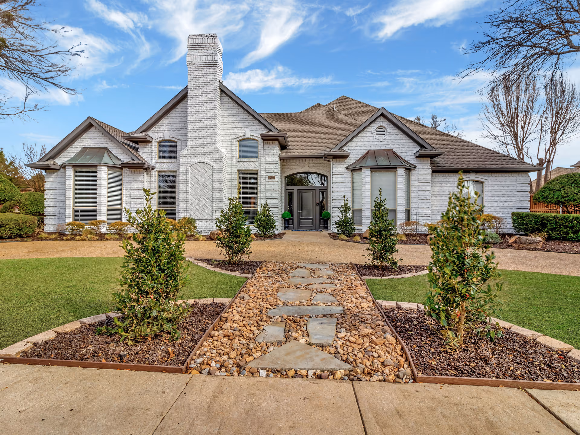 White brick senior living facility with a central entrance and landscaped walkway.