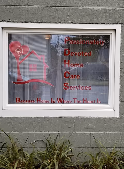 Window sign for Passionately Devoted Home Care Services on a grey exterior wall.