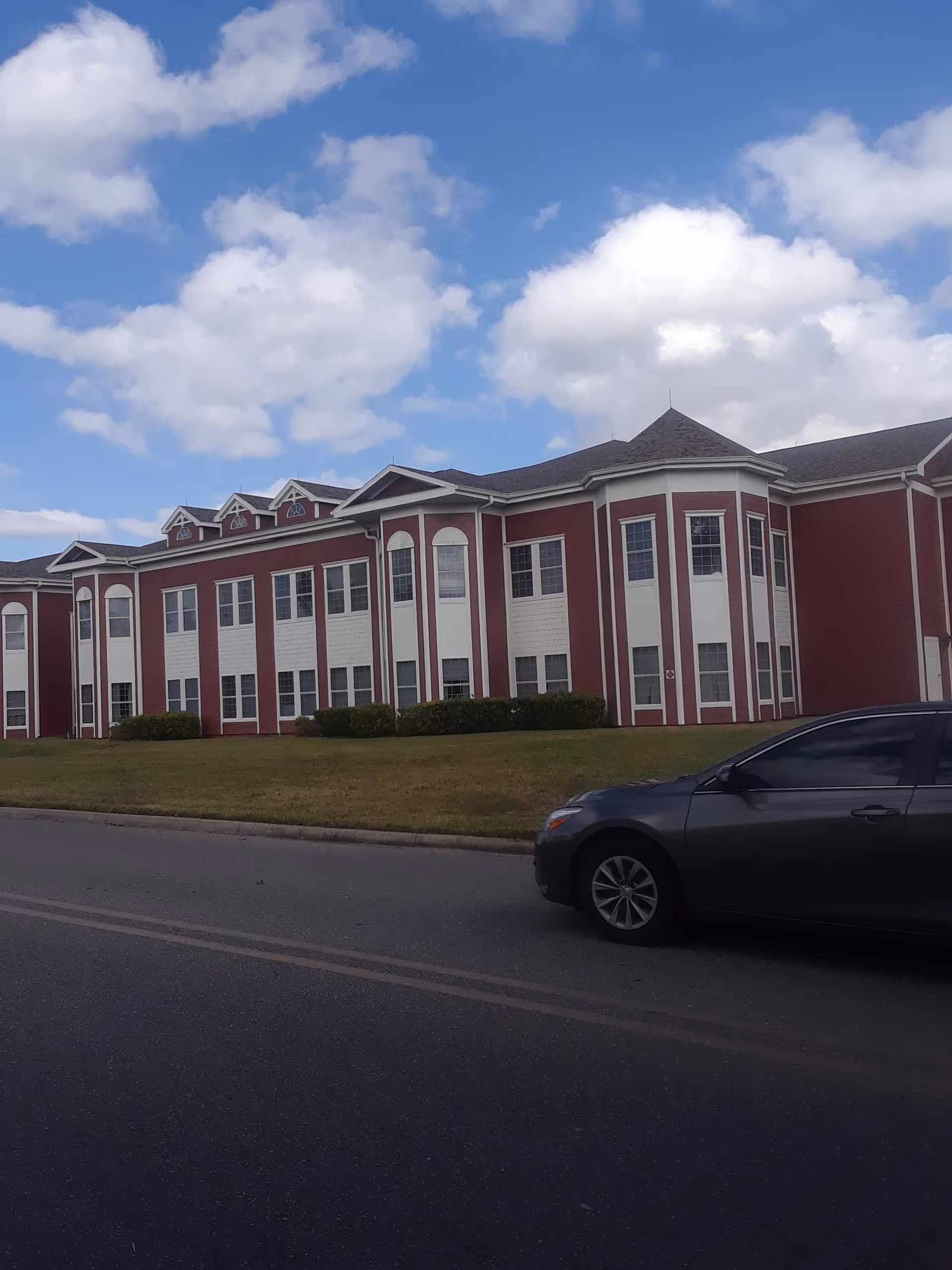 Exterior of Bedrock at Home - Orlando, red-brick senior living facility with a car.