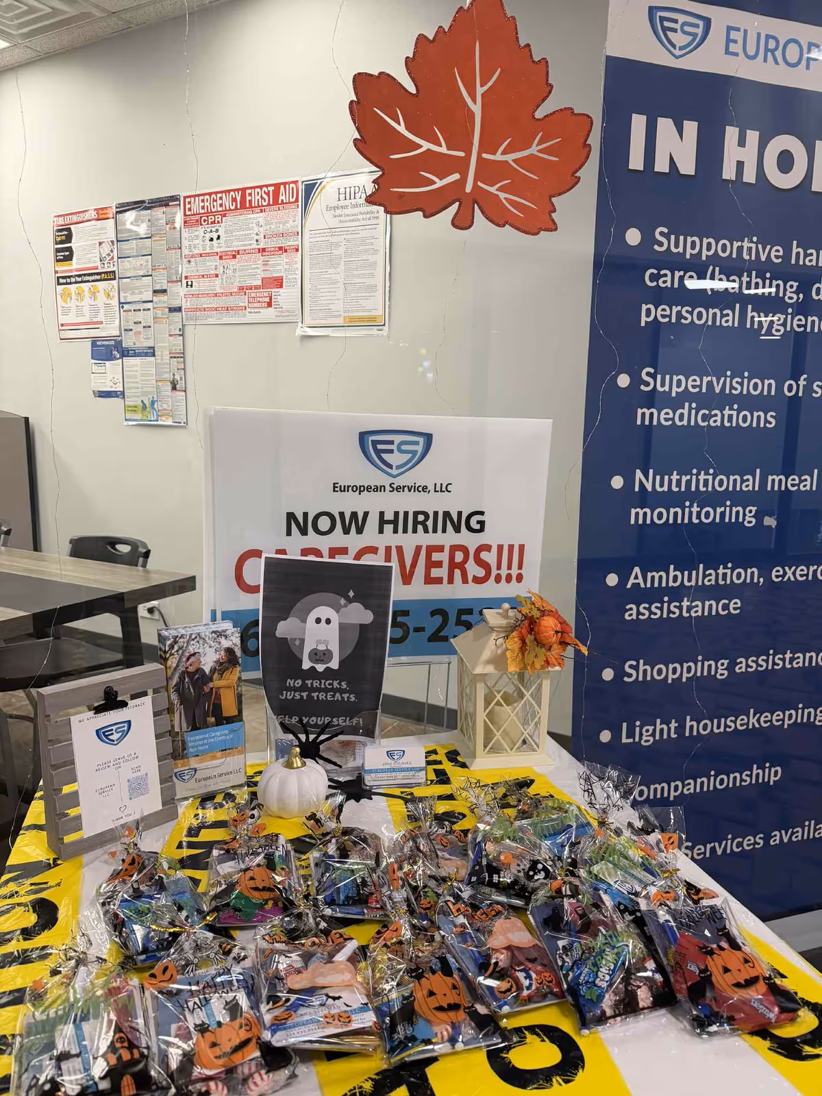 Indoor reception area with job posters, Halloween-themed goody bags, and a banner advertising caregivers.