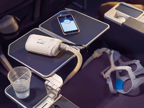 Close-up of a CPAP device on a bedside table with mask and cup.