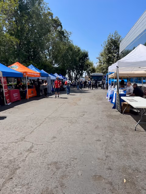 Outdoor event with colorful vendor tents and people walking along a road.