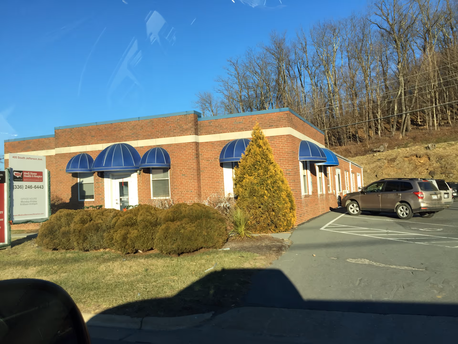Exterior view of Medi Home Health & Hospice building with blue canopy entrances and parking.