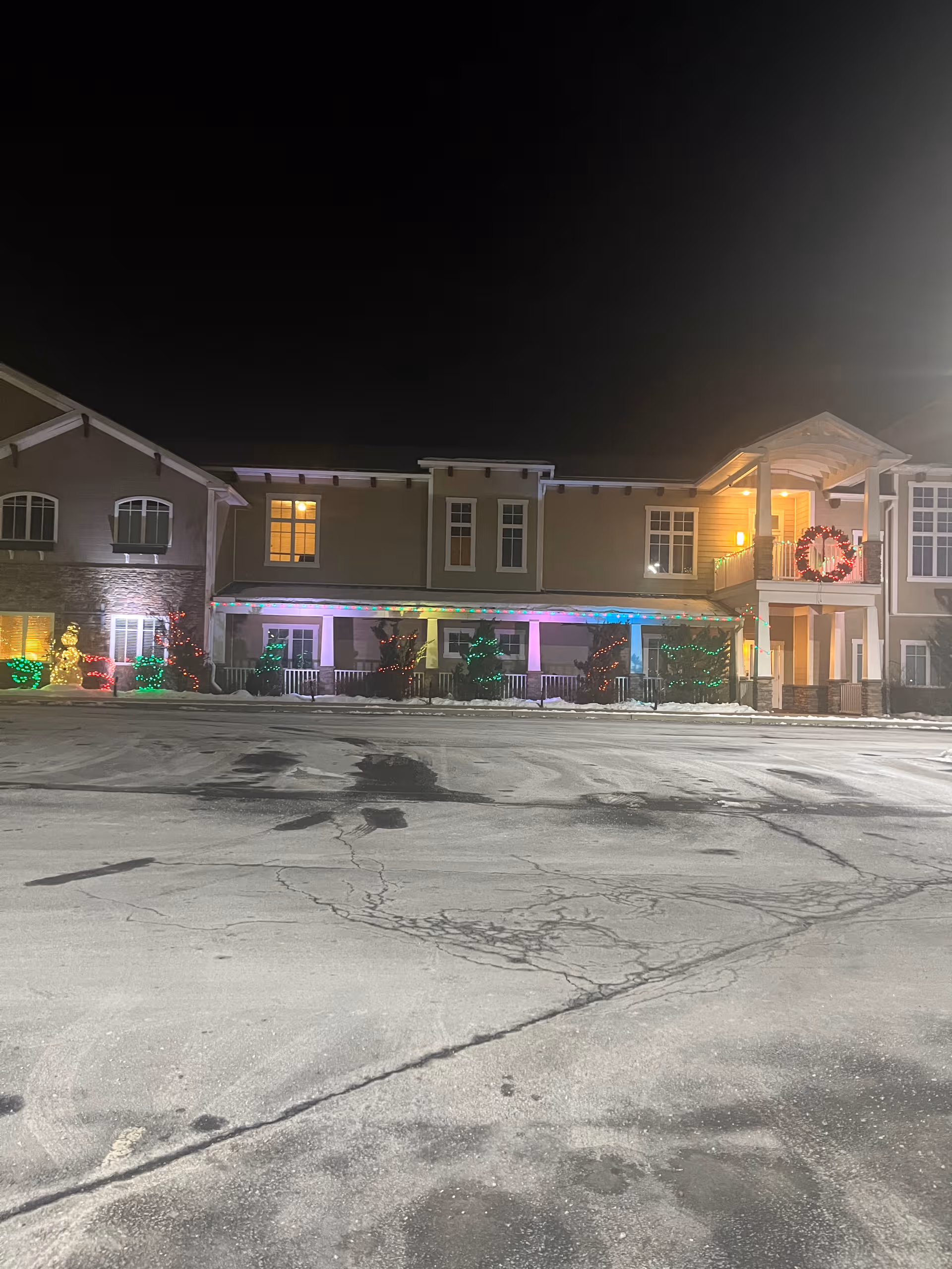Night exterior of Highland Park Senior Living with lit holiday decorations along the front.