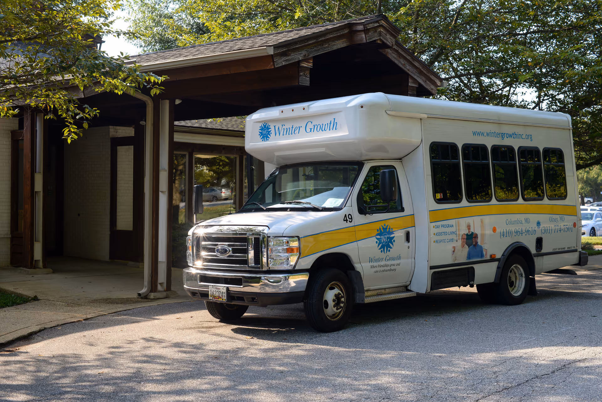 A Winter Growth shuttle bus parked at the covered entrance of a senior living facility.